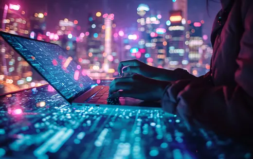 Working on a laptop at night against a neon-lit city skyline